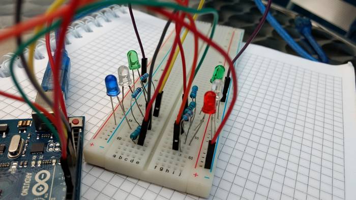 Traffic light circuit assembled on a breadboard with resistors, coloured LEDs, and jumper wires connected to an Arduino Uno microcontroller