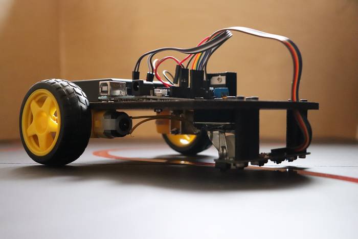 Low angle picture of a line following robot showing motors, wheels, and infrared sensor array